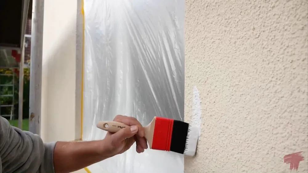 Maler streicht eine Innenwand mit der Rolle