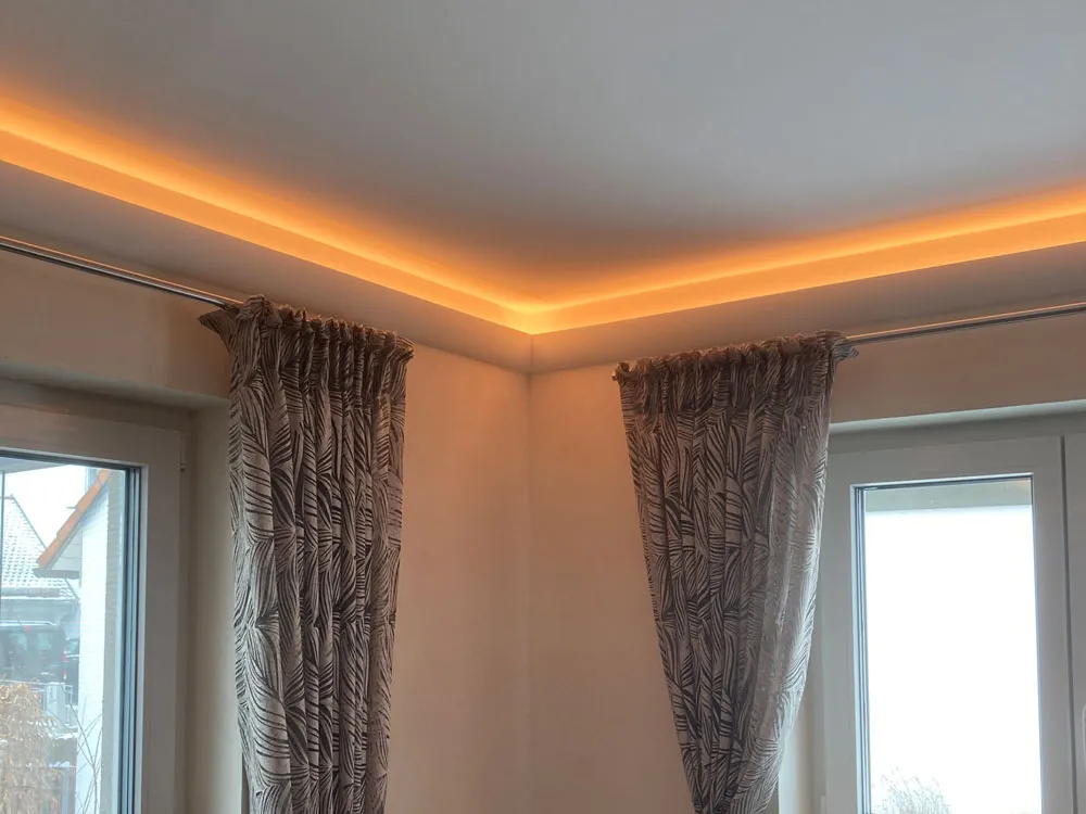 Wohnzimmer mit Stuckleisten und indirekter Beleuchtung an der Decke